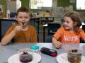 Largs Public School students Charlie Reilly (left) and Sarah Dennis (right) enjoy cultural food tastings for Harmony Day. Picture by Jonathan Carroll
