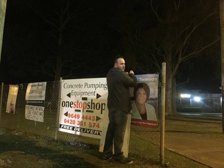CAMPAIGN FLASHPOINT: Jesse Poole, a supporter of the Liberals' Karen Howard, with a poster of Labor's Meryl Swanson that Maitland MP Jenny Aitchison accused him of tampering with on Saturday night. Picture: Jenny Aitchison