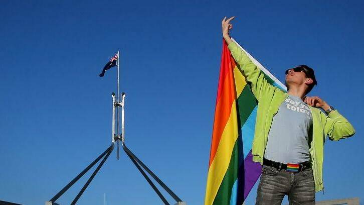 EQUALITY: Marriage equality advocate Russell Nankervis poses for photographers with the rainbow flag on the front lawn of Parliament House in Canberra on Tuesday 8 August 2017. Photo: Alex Ellinghausen