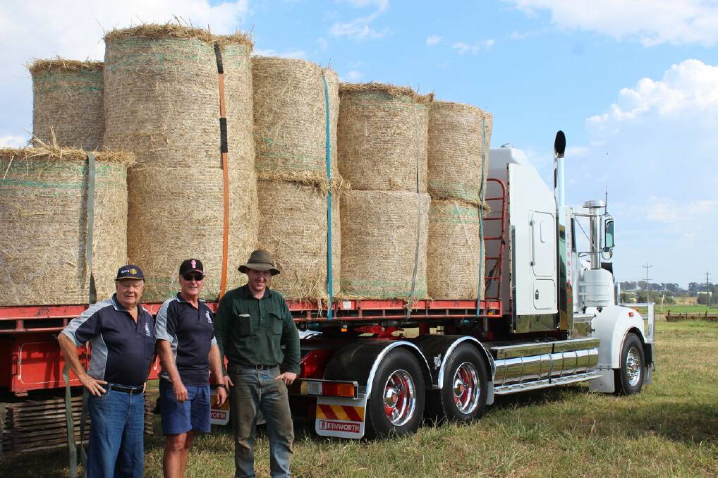 Bob Parsons and Glen Lewis from the Rutherford Telarah Rotary with Hinton farmer Mat Ralston and some of the hay. 