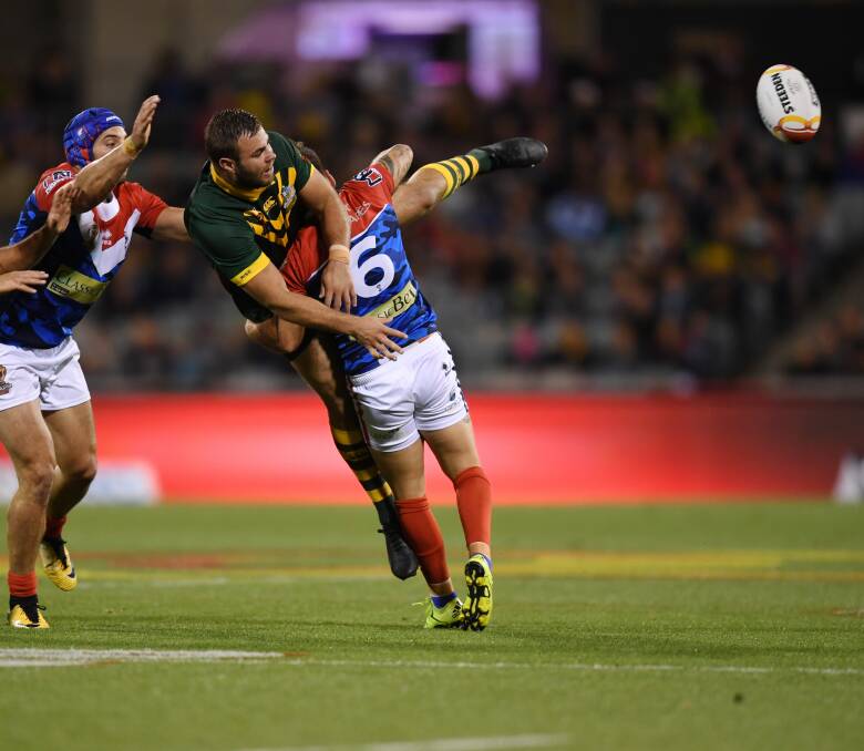 UPLIFTING EXPERIENCE: Wade Graham of the Kangaroos off-loads as he is tackled by Remy Marginet of France in the World Cup showdown at Canberra Stadium on Friday night. Graham scored four tries. Picture: AAP