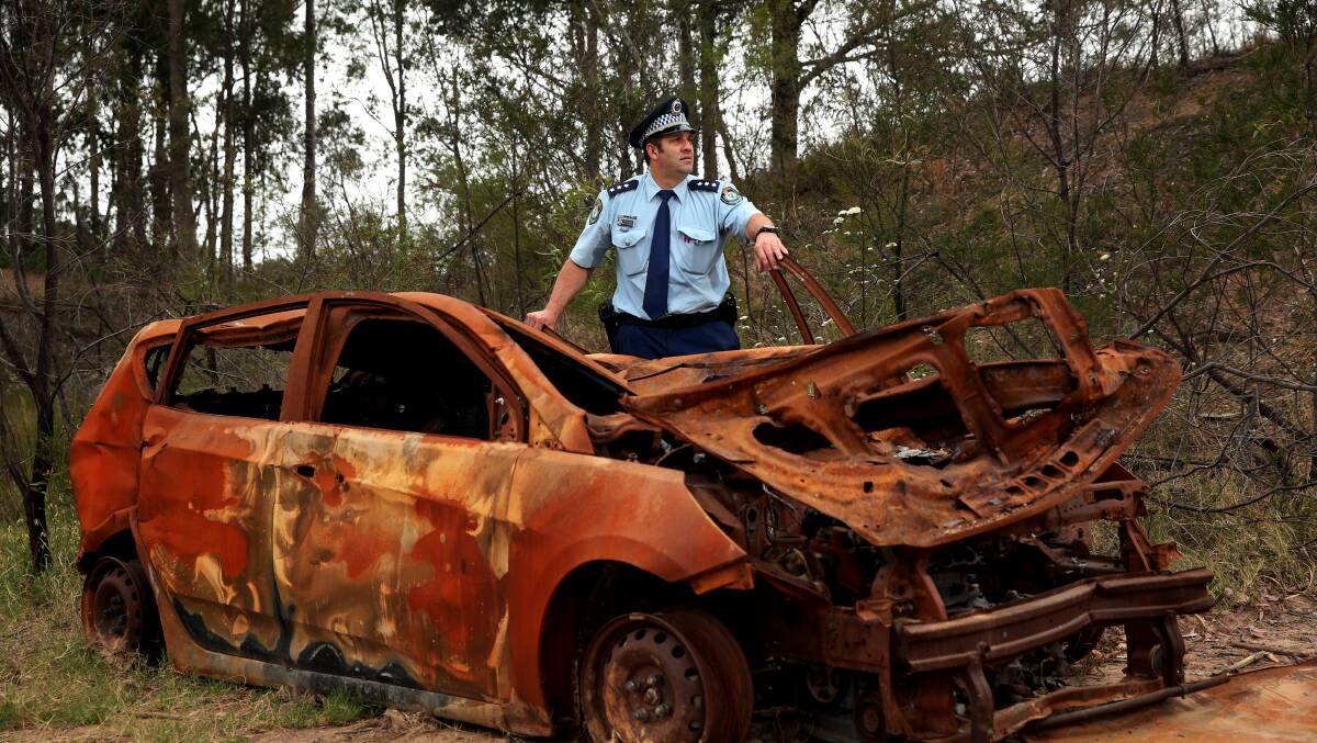 DUMPED: Central Hunter acting crime manager Detective Sergeant Mitch Dubojski with a dumped and burnt out car at Thornton. PICTURE: Simone De Peak.