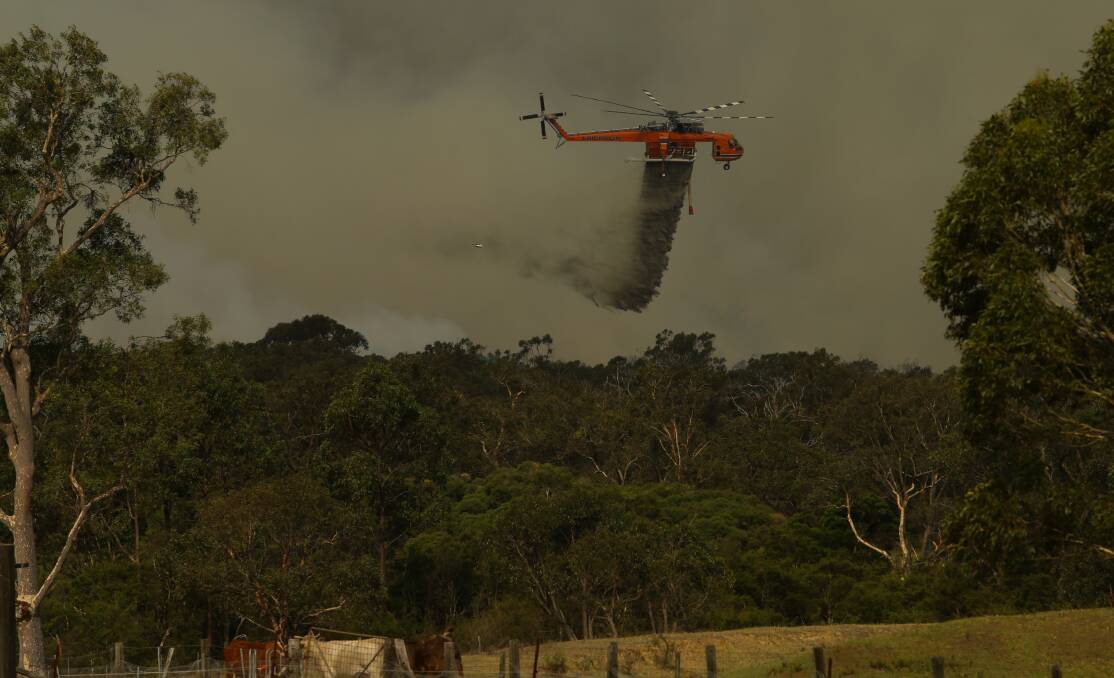 SKY FIGHT: The Rural Fire Service "Skycrane" helicopter drops its water load on top of the fire near Kurri Kurri. Picture: Jonathan Carroll