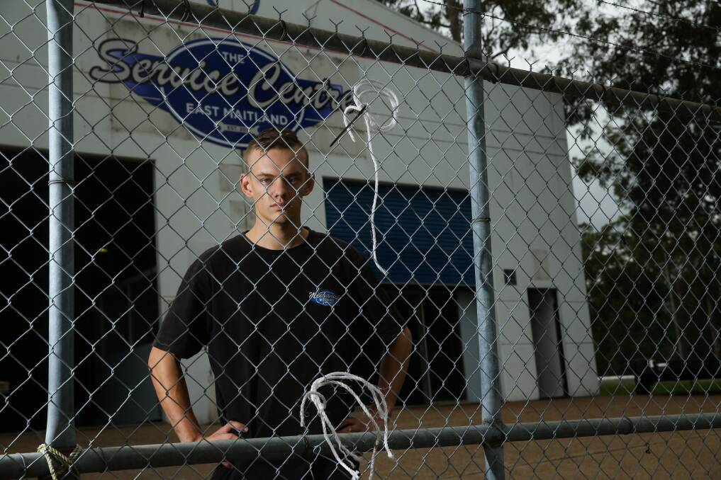 LOW ACT: The Service Centre East Maitland's owner Beau Brannan stands behind the fence from where his signs were stolen. The business opened just three days ago. Picture: Jonathan Carroll