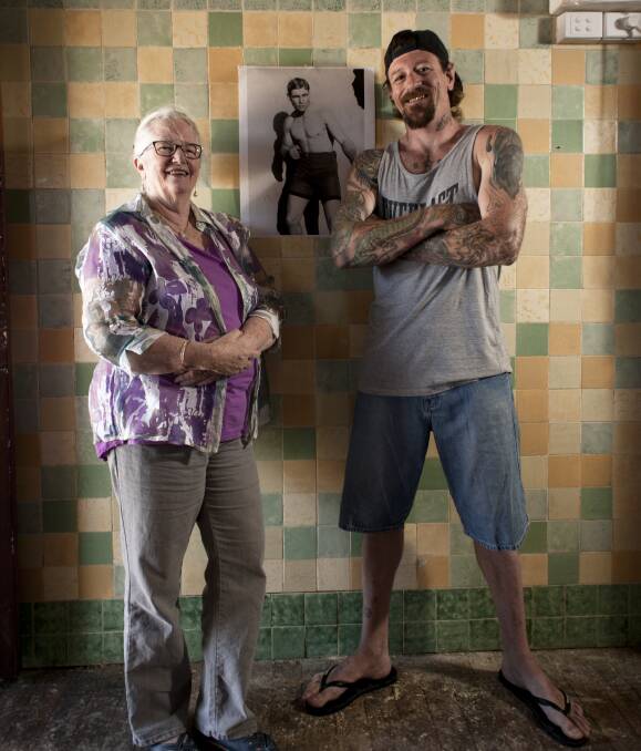 THE LEGEND: Accommodation founder Liz Berger and volunteer Barry Lockett Jnr hang a poster of Les Darcy in the old pub's former bar. It will become a cafe with a mission to help the homeless next month. Picture: Perry Duffin