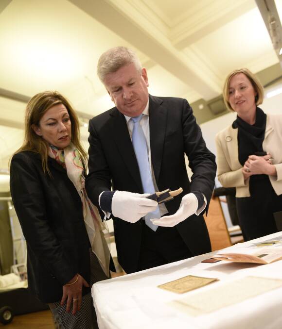 HISTORY: Minister for Arts and Communications Mitch Fifield handles artefacts from the Courage to Care exhibit at MRAG while Liberal candidate Karen Howard and gallery curator Brigette Uren look on. Picture: PERRY DUFFIN