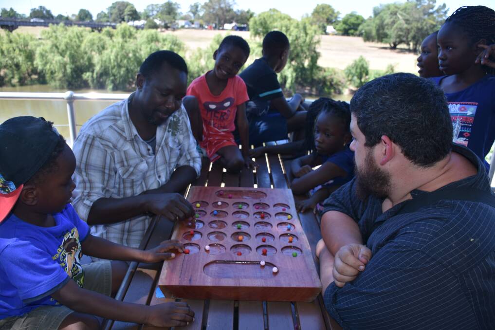 GOOD GAME: Some North Sudanese Maitland residents playing Mancala by the Hunter River on Friday afternoon.