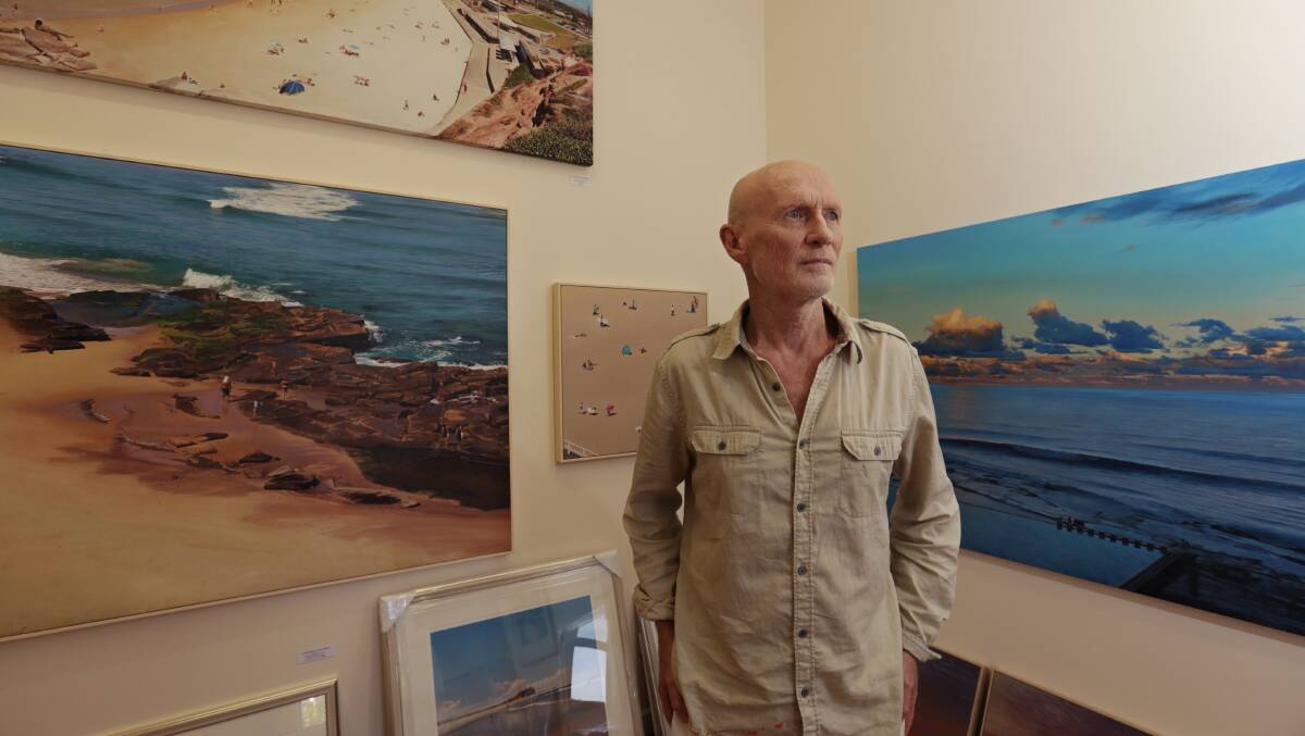 TRADITION: John Earle, in his Merewether gallery with some paintings of local landmarks, which is the art style he is best known for. Picture: Simone De Peak  