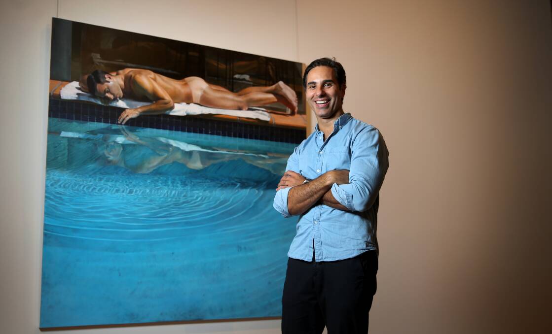 BOLD REFLECTION: Artist Michael Zavros, standing in front of his painted image in The Sunbather, at Newcastle Art Gallery. Picture: Marina Neil