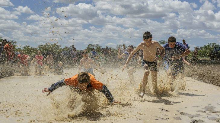 Kids enjoying a race through a mud hole.  For many kids in Walgett. recent rains were the first they have experienced. Photo: Brook Mitchell