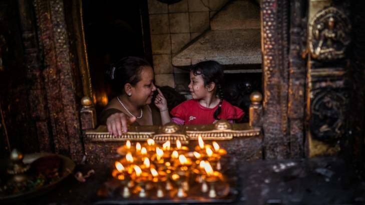 A young girl caresses her mother's nose in a temple  in Kathmandu, Nepal on Monday.  Photo: David Ramos
