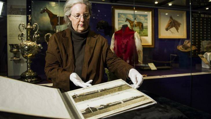 Curator Dr Martha Sear looks at the book of photographs taken by Phar Lap's owner David Davis, which is now on display at the National Museum of Australia.