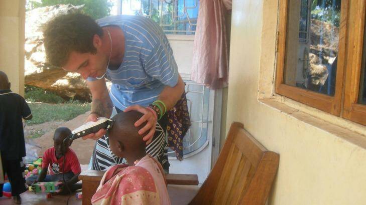 Helping hand: Nathan Bennett, from Melbourne, shaves a boy's head  during his  time as a volunteer at an orphanage in Tanzania.