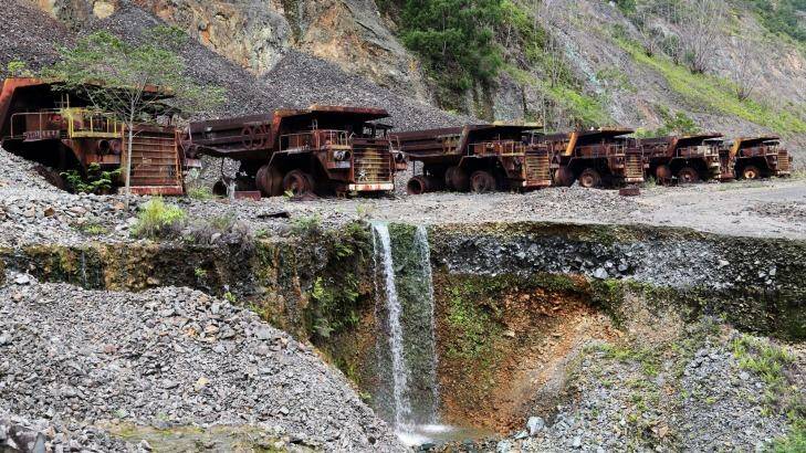 Heavy trucks sit rusting on the edges of Panguna copper mine, closed in 1989 as a result of sabotage. Photo: Friedrich Stark / Alamy Stock Photo