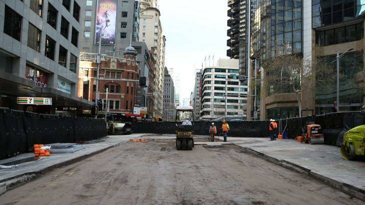 Workers prepare the road surface on Sunday for resealing at the busy intersection on George Street. Photo: James Alcock