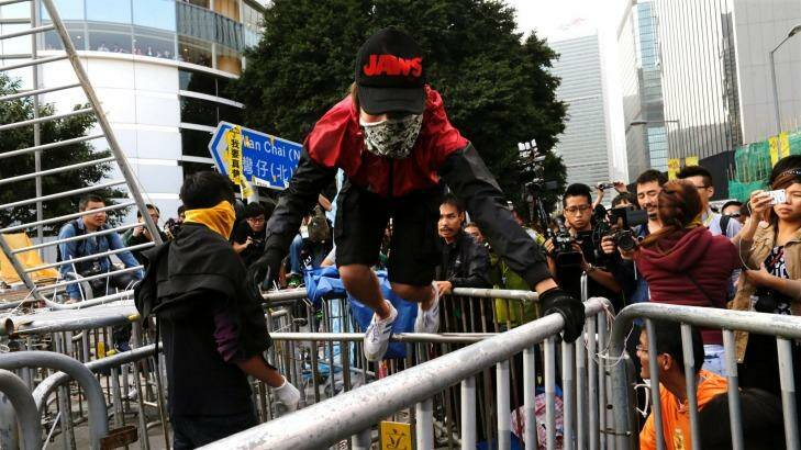 MASKED MAN: A pro-democracy protester climbs on a barricade after the arrival of bailiffs clearing the protest site. Photo: TYRONE SIU / Reuters