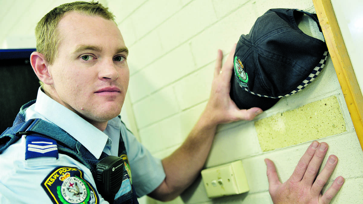 Senior Constable Clinton Walshe and the bullet mark in the brickwork from the shot that wounded Sergeant Jeff Smith many years ago.  