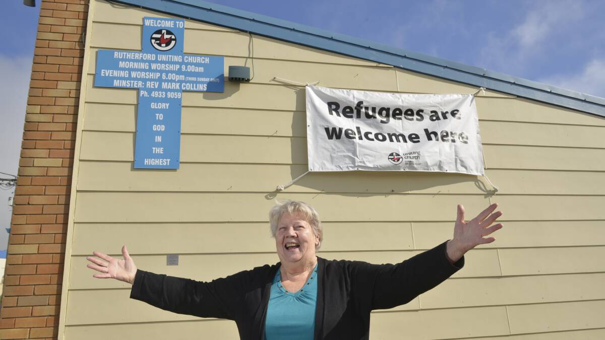 ROOM FOR ALL:  Former church minister Beatrice Esterbrook stands proudly before the new banner.  	Picture by STUART SCOTT 