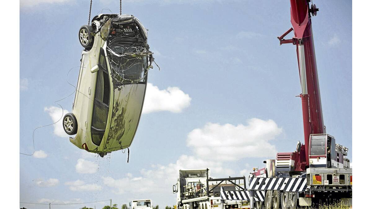 UP AND OUT:  An 80-tonne crane lifts a car from the Hunter River at Bolwarra. 	
	Pictures by PERRY DUFFIN 
