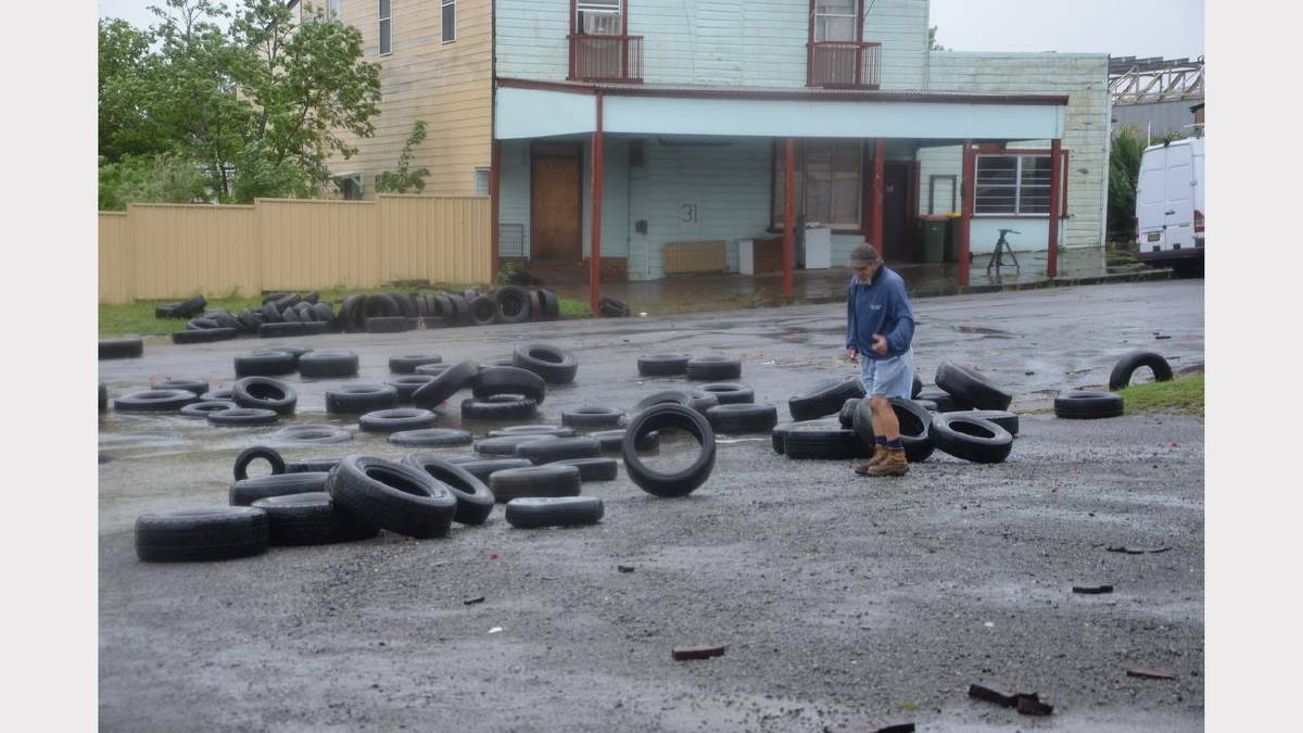 PICK UP: Jack Redman of Dungog Tyre Service, collects tyres that were washed out into Hooke Street.  	Picture JANELLE O’NEILL 
