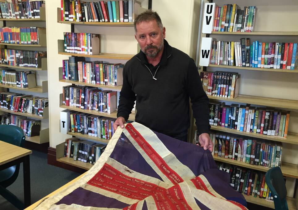 PRIVILEGED:  Tim Weston, principal of Maitland High, with a flag embroidered with the names of students who died in the war.  	Picture by ALAN HARDIE 