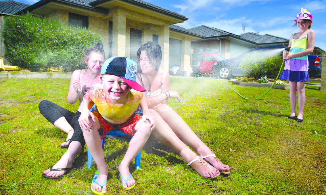COOLING OFF: Porsha Delmege cools Taylor Saxby, Aiden Delmege and Tarly Coughlin with the hose on Sunday at her Aberglasslyn home.