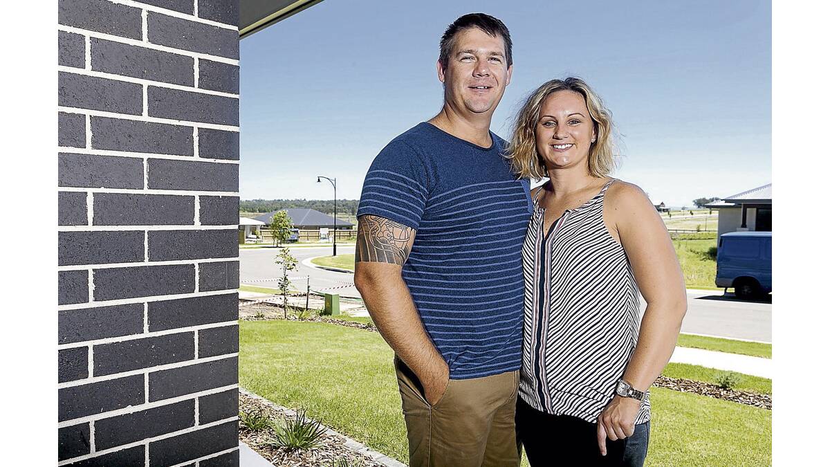 AT HOME: Kate Moore and her partner Travis outside their new home in the Harvest estate at Chisholm.  	