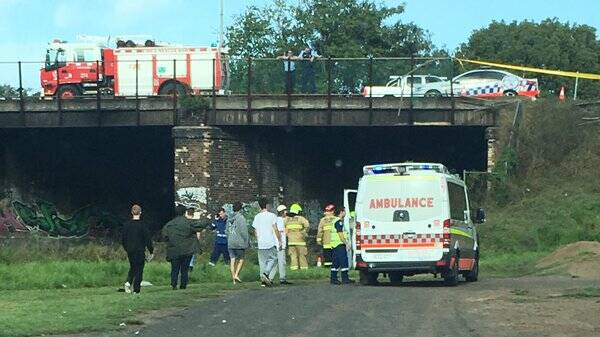 Emergency crews at the overpass in Maitland, where a car plummeted onto the train tracks. Picture: PHILIP PENFOLD