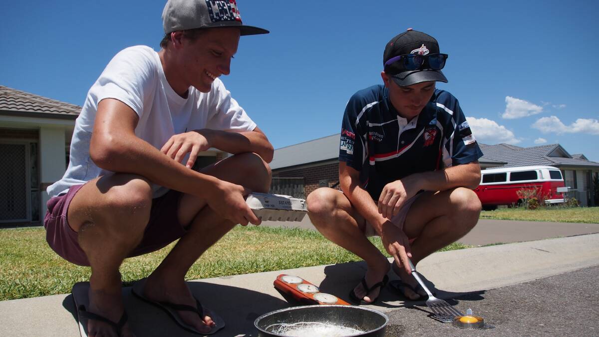 Rhys Tickle, 15, and Callum Woodbury, 17, attempt to fry an egg on the road at McKeachie's Run in 40-plus degree heat. Picture: Nick Bielby