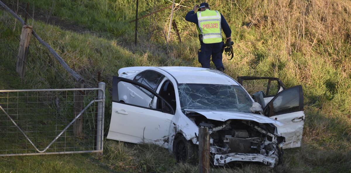 TRAGEDY: A police officer at the scene of a crash where a car left the New England Highway at Maitland and entered Wallis Creek. Picture: Perry Duffin