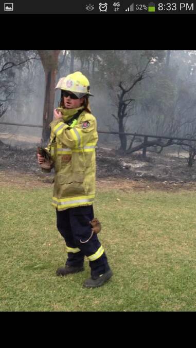 Firefighter Matt Weigner at the Gateshead fire on Thursday.  (Note the small ring-tailed possum clinging to his leg) Picture from Facebook sent in by Georgia Kelly