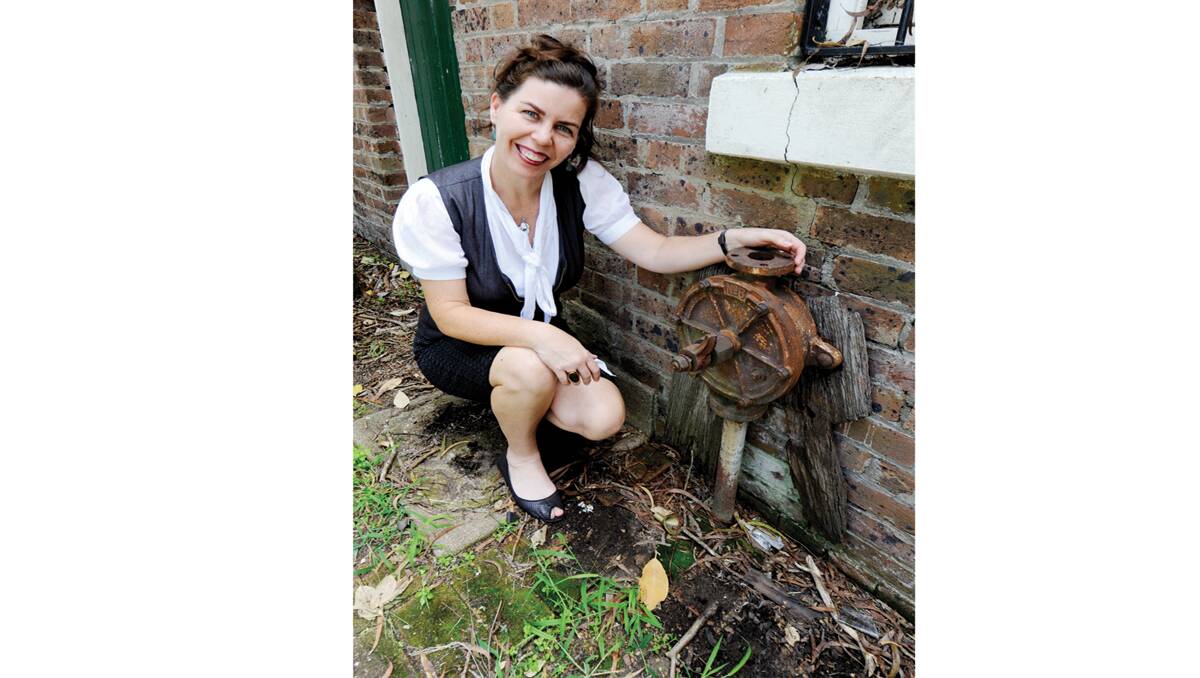 LOOKING AT OUR PAST:  Council heritage officer Clare James at the Victorian pump attached to a wall that had been covered over.    