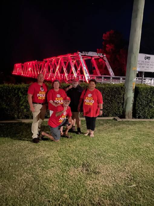 Members of the Rotary Club of East Maitland in front of Morpeth Bridge, which is lit up for End Polio Day. Picture supplied