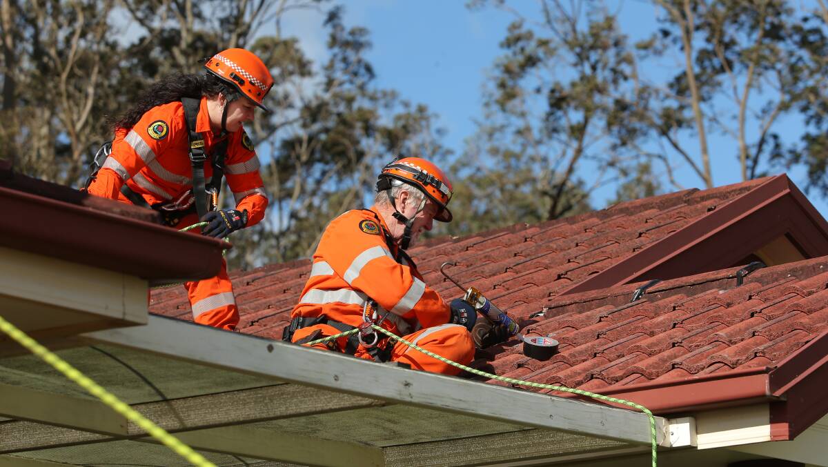 CLEANING UP: An SES crew working on a roof in Rutherford on Tuesday. Picture: Simone De Peak.