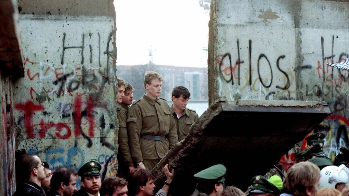 East German border guards look through a hole in the Berlin Wall after demonstrators pulled down the segment at Brandenburg Gate in Berlin. Picture by AP Photo/Lionel Cironneau