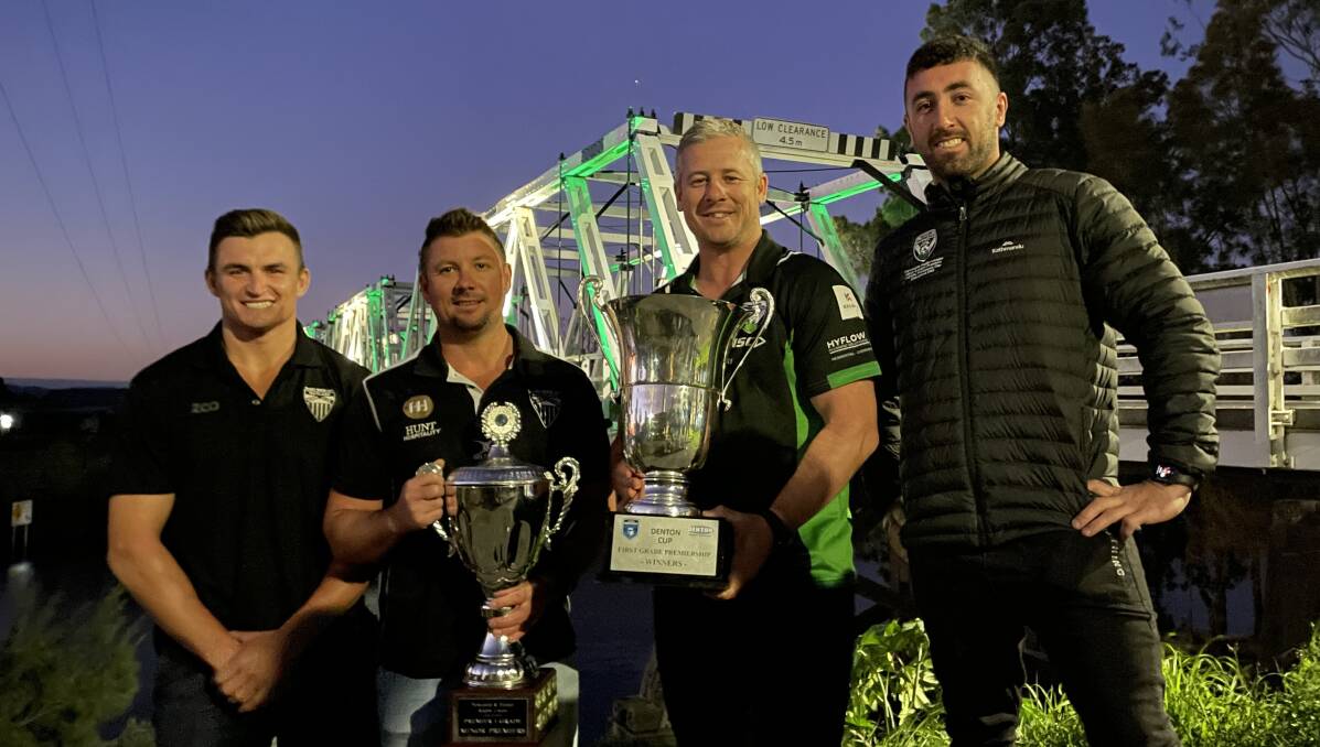 From left, Maitland Blacks captain Sam Callow, coach Luke Cunningham, Pickers coach Matt Lantry and Pickers halfback Brock Lamb with their premiership trophies at the Morpeth Bridge. Picture by Ben Carr
