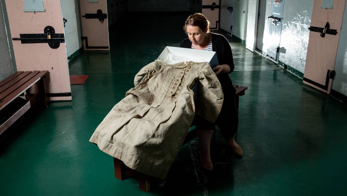NEW EXHIBITION: Maitland Gaol's service delivery officer Zoe Whiting with a women's straight dress which is believed to be the only one in the state. Picture: Marina Neil
