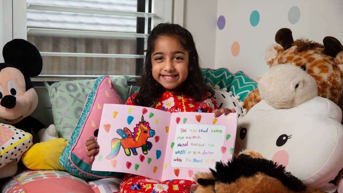 Work of art: Laila and her book about a flying unicorn. Picture: Marina Neil.
