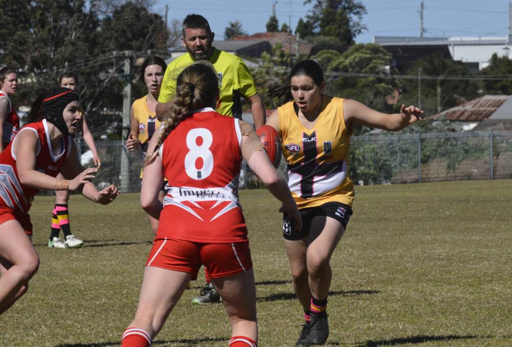 GUN: Sarah Burns gets her kick in despite pressure from a Singleton opponent. Burns kicked four of Maitland seven goals in the 41-point win against the Roosters. Picture: Michael Hartshorn