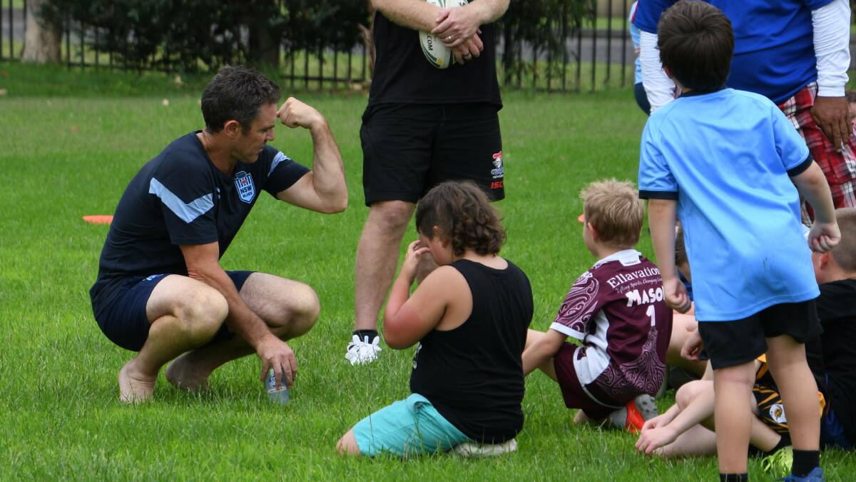 MUSCLE POWER: NSW Blues coach Brad Fittler flexes his muscles to the delight of his young charges at Kurri Kurri Sportsground. Picture: Michael Hartshorn
