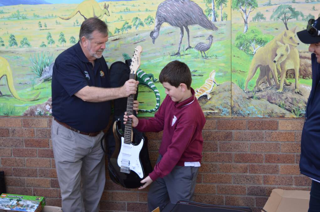 MUSIC TO THEIR EARS: Rural Aid general manager Wayne Thomson (left) presents a guitar courtesy of the charity's Gift of Music program. 