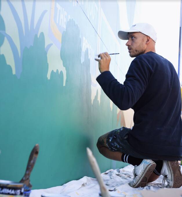 HISTORY IN THE MAKING: Newcastle artist Mitch "Revs" Resevsky works on a mural of the Hunter Valley at The Bradford Hotel in Rutherford. Picture: Sean Fox