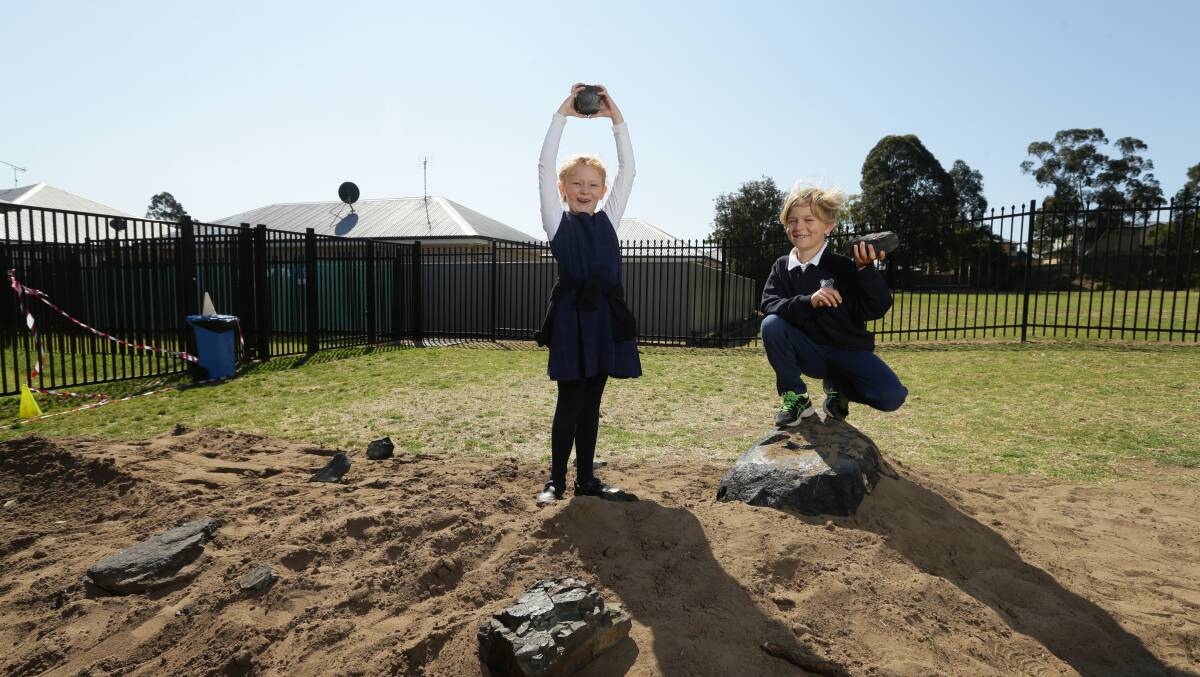 EXCITEMENT: East Maitland Public School students Amelia Cummings and Nixon Perrin with the meteorite in the school playground. Picture: Jonathan Carroll