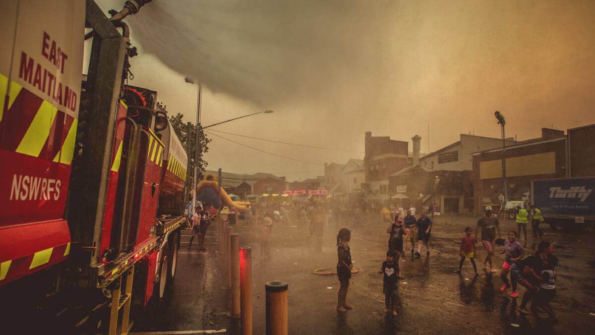 STEAMY: East Maitland RFS crews cooling down New Year's Eve revelers in Maitland. The high temperatures forced the cancellation of the city's fireworks display. Picture: Marina Neil