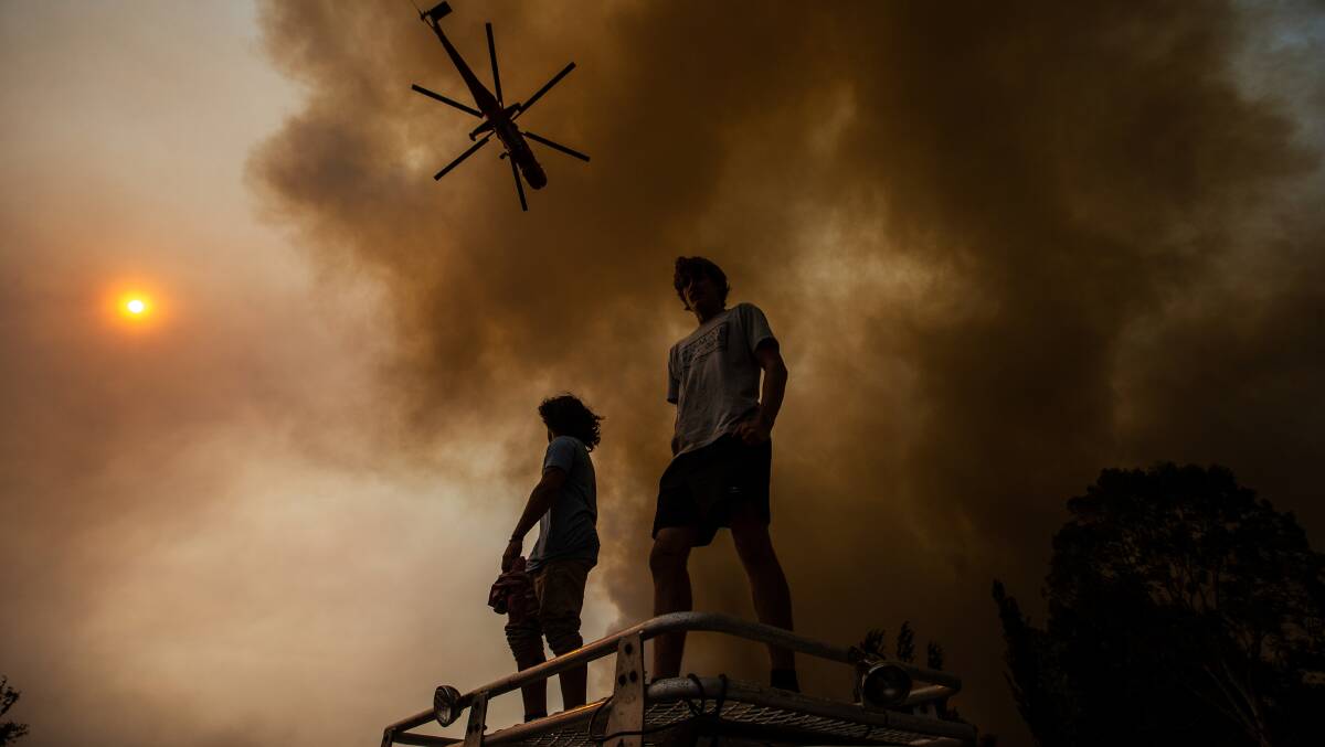 SMOKE: Residents watch on as a water-bombing helicopter flies over them to fight the fire at Pelaw Main.