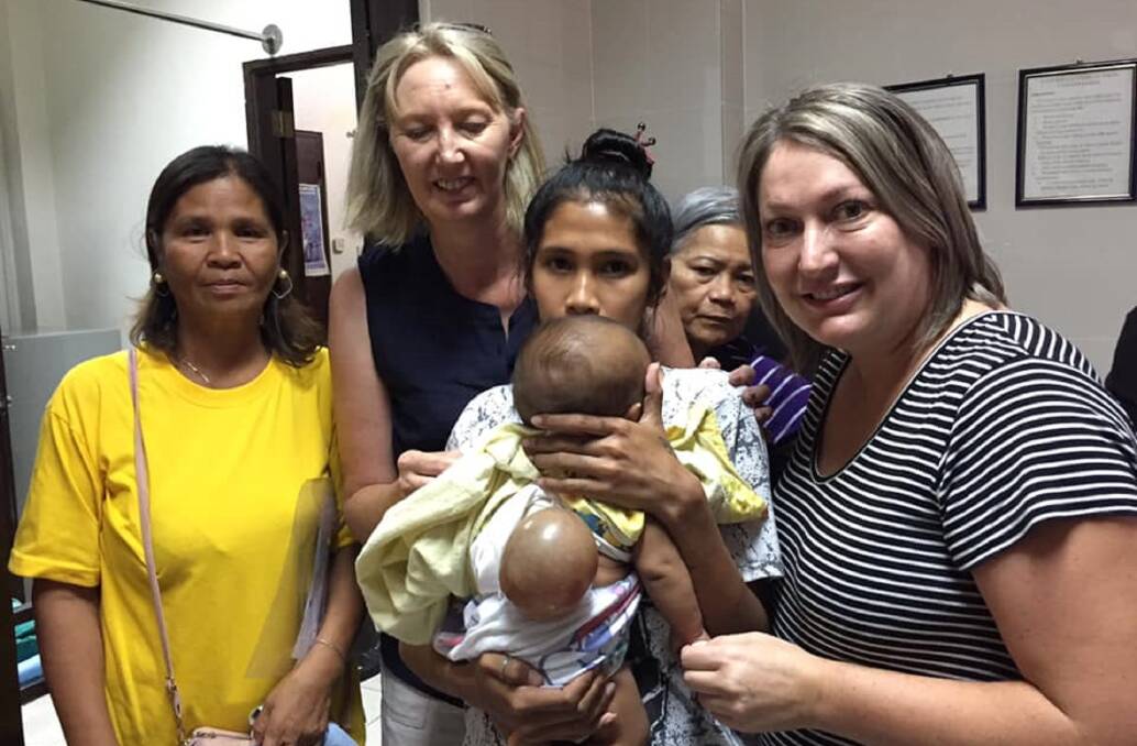TOUCHING: Heidi Avery (right) and Sonya Mervin (second left) pictured with a mother and her infant child who needed a tumour removed.