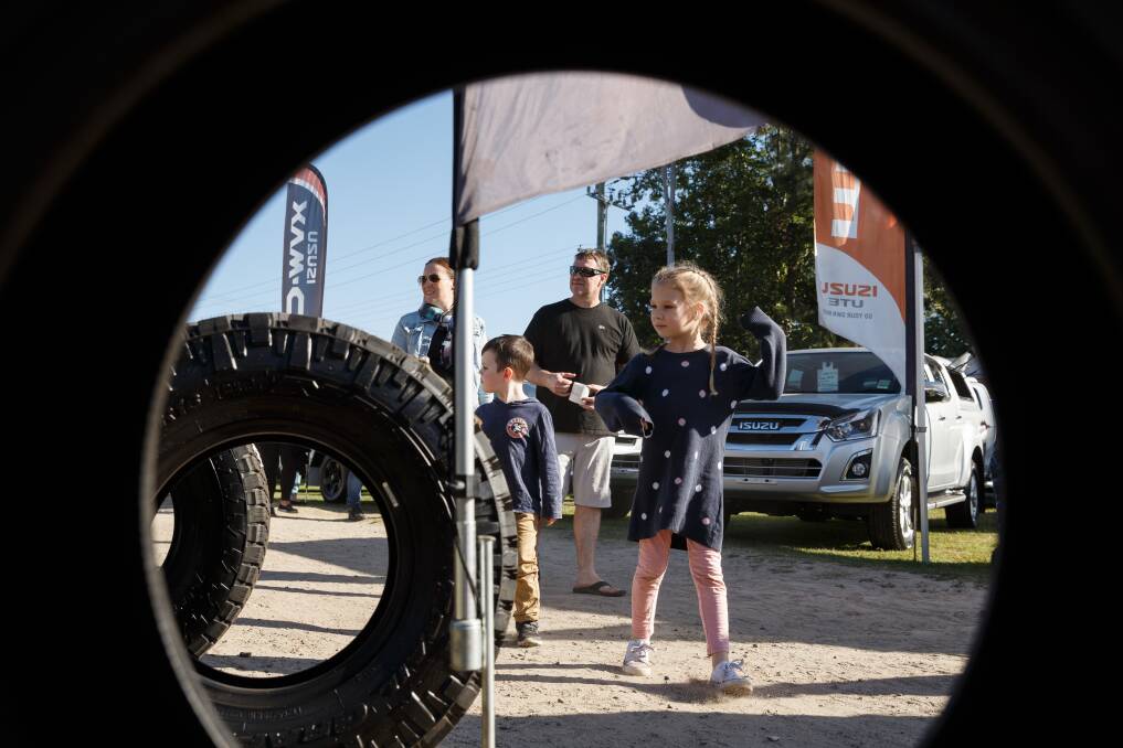HAPPY CAMPERS: Lilly Bellamy, 6, of Singleton, checks out some 4WD tyres while her family walks behind at this year's Hunter Valley Caravan, Camping, Fish, 4WD and Boat Show. Pictures: Max Mason Hubers.