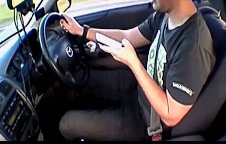 CAUGHT IN THE ACT: A driver texting behind the wheel. 