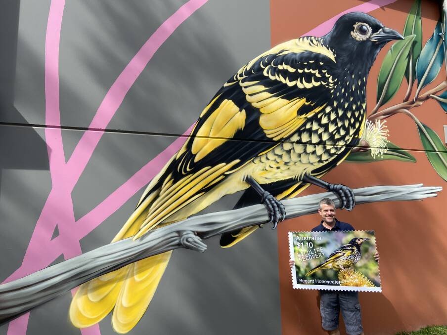 UNDER PRESSURE: Mick Roderick stands beside the magnificent mural of a Regent Honeyeater at Pokolbin Distillery in Pokolbin, with an oversized version of the new stamp.
