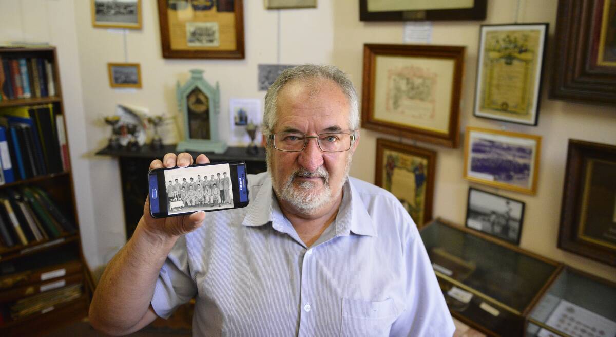 Memories: Paul holds up a photo of the Greta soccer team including his father, which represented the migrant camp. Picture: Lachlan Leeming